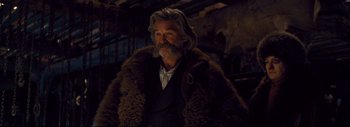 Movie still from “The Hateful Eight” (2015), directed by Quentin Tarantino – A man with long hair and a beard wearing a fur coat; Medium shot, Over the shoulder angle