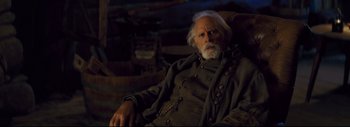 Movie still from “The Hateful Eight” (2015), directed by Quentin Tarantino – An old man sitting in a chair with a chain around his neck; Close Up shot, Over the shoulder angle