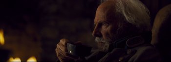 Movie still from “The Hateful Eight” (2015), directed by Quentin Tarantino – An old man holding a cup in his hands; Close Up shot, Over the shoulder angle