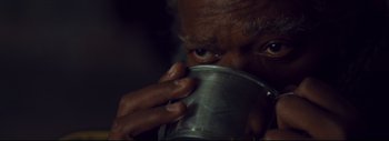 Movie still from “The Hateful Eight” (2015), directed by Quentin Tarantino – An older man is drinking from a metal cup; Extreme Close Up shot, High angle