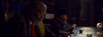 Movie still from “The Hateful Eight” (2015), directed by Quentin Tarantino – Two men sitting at a table in a dark room; Close Up shot, Over the shoulder angle