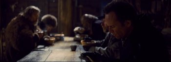Movie still from “The Hateful Eight” (2015), directed by Quentin Tarantino – A group of people sitting at a table with bowls of food; Close Up shot, Over the shoulder angle