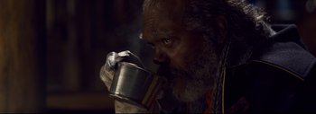 Movie still from “The Hateful Eight” (2015), directed by Quentin Tarantino – An older man drinking from a metal cup; Extreme Close Up shot, Low angle
