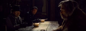 Movie still from “The Hateful Eight” (2015), directed by Quentin Tarantino – A man sitting at a table with two bowls of soup; Medium shot, Over the shoulder angle