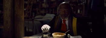 Movie still from “The Hateful Eight” (2015), directed by Quentin Tarantino – An older man sitting at a table with a bowl of food; Close Up shot, High angle