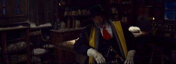 Movie still from “The Hateful Eight” (2015), directed by Quentin Tarantino – A man in a black hat and a yellow coat; Medium shot, Low angle