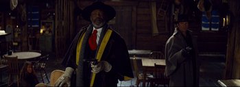 Movie still from “The Hateful Eight” (2015), directed by Quentin Tarantino – A man dressed as a cowboy holding a gun in his hand; Medium shot, Low angle