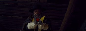 Movie still from “The Hateful Eight” (2015), directed by Quentin Tarantino – A man in a black hat holding a pair of pistols in his hands; Medium shot, Low angle