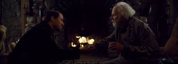 Movie still from “The Hateful Eight” (2015), directed by Quentin Tarantino – Two men sitting in front of a fire place; Medium shot, Over the shoulder angle