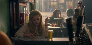 Movie still from “The Haunting of Bly Manor” (2020), directed by E.L. Katz – A woman sitting at a table with a glass of beer in front of her; Medium shot, Over the shoulder angle