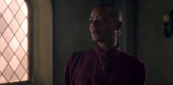 A woman in a red shirt is standing in a dark room