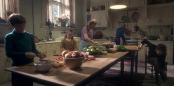 Movie still from “The Haunting of Bly Manor” (2020), directed by E.L. Katz – A woman and two children preparing food in a kitchen; Wide shot, High angle