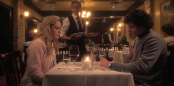 Movie still from “The Haunting of Bly Manor” (2020), directed by E.L. Katz – A couple of people sitting at a table with wine glasses; Medium shot, Over the shoulder angle
