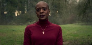 Movie still from “The Haunting of Bly Manor” (2020), directed by E.L. Katz – A woman in a red shirt with a gold cross necklace; Close Up shot, Over the shoulder angle