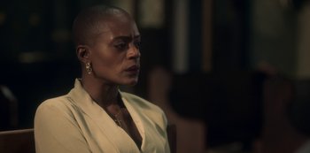 Movie still from “The Haunting of Bly Manor” (2020), directed by E.L. Katz – An older woman with short black hair wearing a white jacket; Close Up shot, Over the shoulder angle