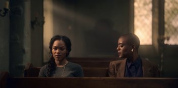 Movie still from “The Haunting of Bly Manor” (2020), directed by E.L. Katz – Two people sitting in a church pews looking at each other; Medium shot, Over the shoulder angle