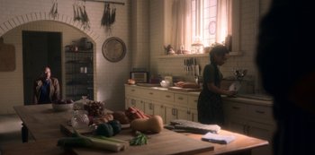 Movie still from “The Haunting of Bly Manor” (2020), directed by E.L. Katz – A woman standing in a kitchen preparing a meal; Wide shot, High angle