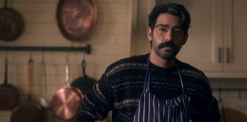 Movie still from “The Haunting of Bly Manor” (2020), directed by E.L. Katz – A man in a kitchen wearing an apron and glasses; Close Up shot, Over the shoulder angle