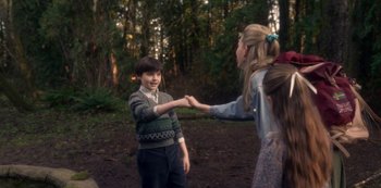 A boy and a girl holding hands in the woods