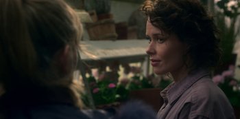 Movie still from “The Haunting of Bly Manor” (2020), directed by E.L. Katz – A woman standing next to another woman in front of flowers; Close Up shot, Over the shoulder angle