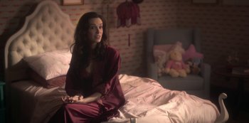 Movie still from “The Haunting of Bly Manor” (2020), directed by E.L. Katz – A woman sitting on top of a bed next to a teddy bear; Medium shot, High angle