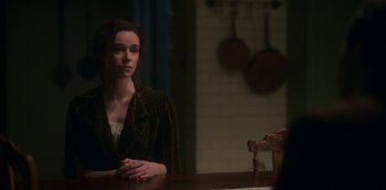 Movie still from “The Haunting of Bly Manor” (2020), directed by E.L. Katz – A woman sitting at a table in front of pots; Medium shot, Over the shoulder angle