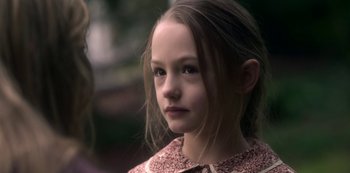Movie still from “The Haunting of Bly Manor” (2020), directed by E.L. Katz – A little girl with long brown hair looking at the camera; Close Up shot, Over the shoulder angle