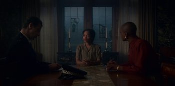Movie still from “The Haunting of Bly Manor” (2020), directed by E.L. Katz – A group of people sitting at a wooden table in front of a window; Medium shot, Over the shoulder angle