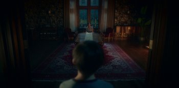 Movie still from “The Haunting of Bly Manor” (2020), directed by E.L. Katz – A man sitting at a dining room table in front of a window; Wide shot, Over the shoulder angle