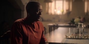 Movie still from “The Haunting of Bly Manor” (2020), directed by E.L. Katz – A person sitting at a table in a room; Close Up shot, Low angle