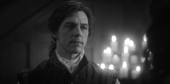 Movie still from “The Haunting of Bly Manor” (2020), directed by E.L. Katz – Black and white photograph of a man with long dark hair; Close Up shot, Over the shoulder angle