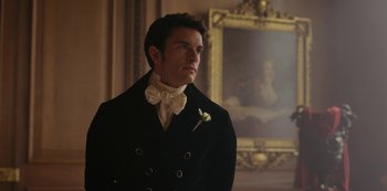 Movie still from “Bridgerton” (2020), created by Chris Van Dusen – A man wearing a suit and bow tie in front of a painting; Close Up shot, Low angle