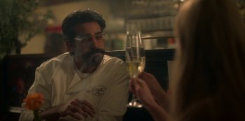 Movie still from “The Haunting of Bly Manor” (2020), directed by E.L. Katz – A man and a woman sitting at a table with drinks; Close Up shot, Over the shoulder angle