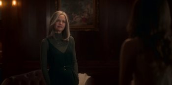 Movie still from “The Haunting of Bly Manor” (2020), directed by E.L. Katz – A woman standing in front of a painting in a dark room; Medium shot, Over the shoulder angle