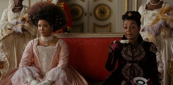 Movie still from “Bridgerton” (2020), created by Chris Van Dusen – Two women sitting next to each other on a couch; Medium shot, Over the shoulder angle