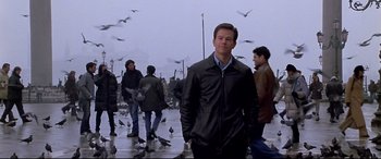 Movie still from “The Italian Job” (2003), directed by F. Gary Gray – A group of people walking on a sidewalk near a flock of birds; Medium shot, Low angle