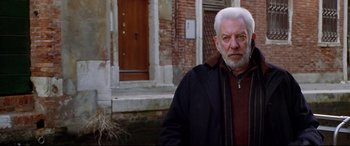 Movie still from “The Italian Job” (2003), directed by F. Gary Gray – An older man standing in front of a brick building; Medium shot, Low angle