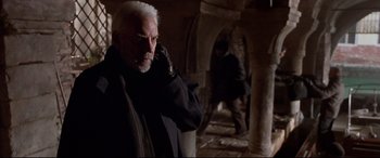 Movie still from “The Italian Job” (2003), directed by F. Gary Gray – An older man with a white beard is talking on a cell phone; Medium shot, Low angle