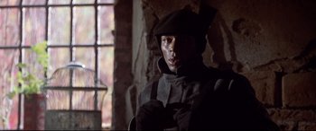 Movie still from “The Italian Job” (2003), directed by F. Gary Gray – A man wearing a hat and gloves in front of a brick wall; Close Up shot, Low angle
