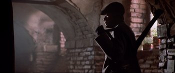 Movie still from “The Italian Job” (2003), directed by F. Gary Gray – A man wearing a hat and a jacket standing in front of a brick wall; Close Up shot, Low angle