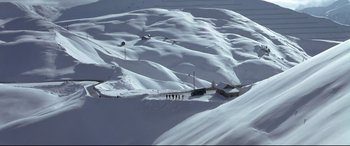 Movie still from “The Italian Job” (2003), directed by F. Gary Gray – A group of people standing on top of a snow covered slope; Extreme Wide shot, High angle