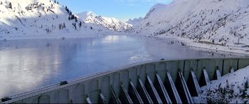 Movie still from “The Italian Job” (2003), directed by F. Gary Gray – A view of a lake with snow on the mountains behind it; Extreme Wide shot, High angle