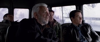 Movie still from “The Italian Job” (2003), directed by F. Gary Gray – An older man sitting in a bus with two other men; Medium shot, Over the shoulder angle