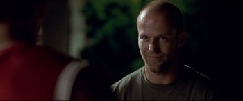 Movie still from “The Italian Job” (2003), directed by F. Gary Gray – A man with a shaved head is smiling for the camera; Close Up shot, Over the shoulder angle