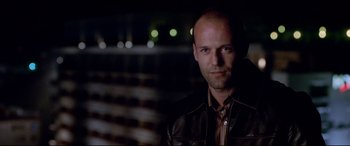 Movie still from “The Italian Job” (2003), directed by F. Gary Gray – A man wearing a leather jacket is looking at the camera; Close Up shot, Over the shoulder angle