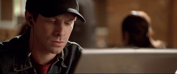 Movie still from “The Italian Job” (2003), directed by F. Gary Gray – A young man wearing a baseball cap looking at a computer screen; Close Up shot, High angle