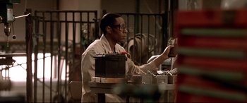 Movie still from “The Italian Job” (2003), directed by F. Gary Gray – A man in a white shirt is working in a factory; Medium shot, Low angle