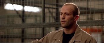 Movie still from “The Italian Job” (2003), directed by F. Gary Gray – A bald man with a beard is standing in a warehouse; Close Up shot, Low angle