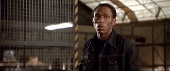 Movie still from “The Italian Job” (2003), directed by F. Gary Gray – A man in a black shirt and black jacket looking to his left; Close Up shot, Low angle