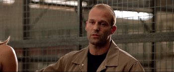 Movie still from “The Italian Job” (2003), directed by F. Gary Gray – A man with a shaved head is looking at the camera; Close Up shot, Low angle